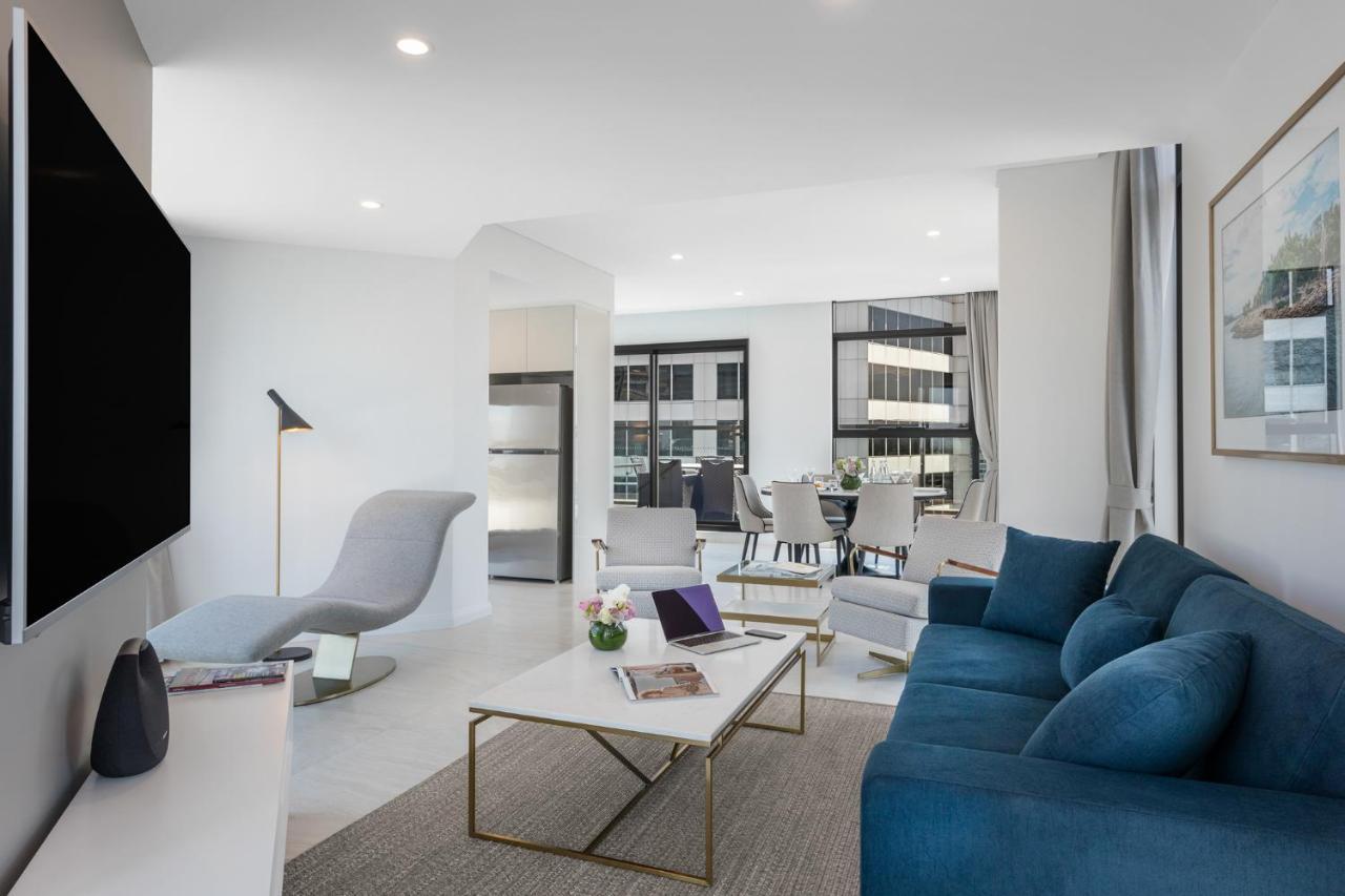 Meriton Suites Sussex Street, Sydney Exteriér fotografie The photo shows a modern living space that features a bright and stylish interior. Key elements include:

- A sleek blue sofa and a light gray lounge chair, providing comfortable seating.
- A coffee table with a minimalist design, positioned in front