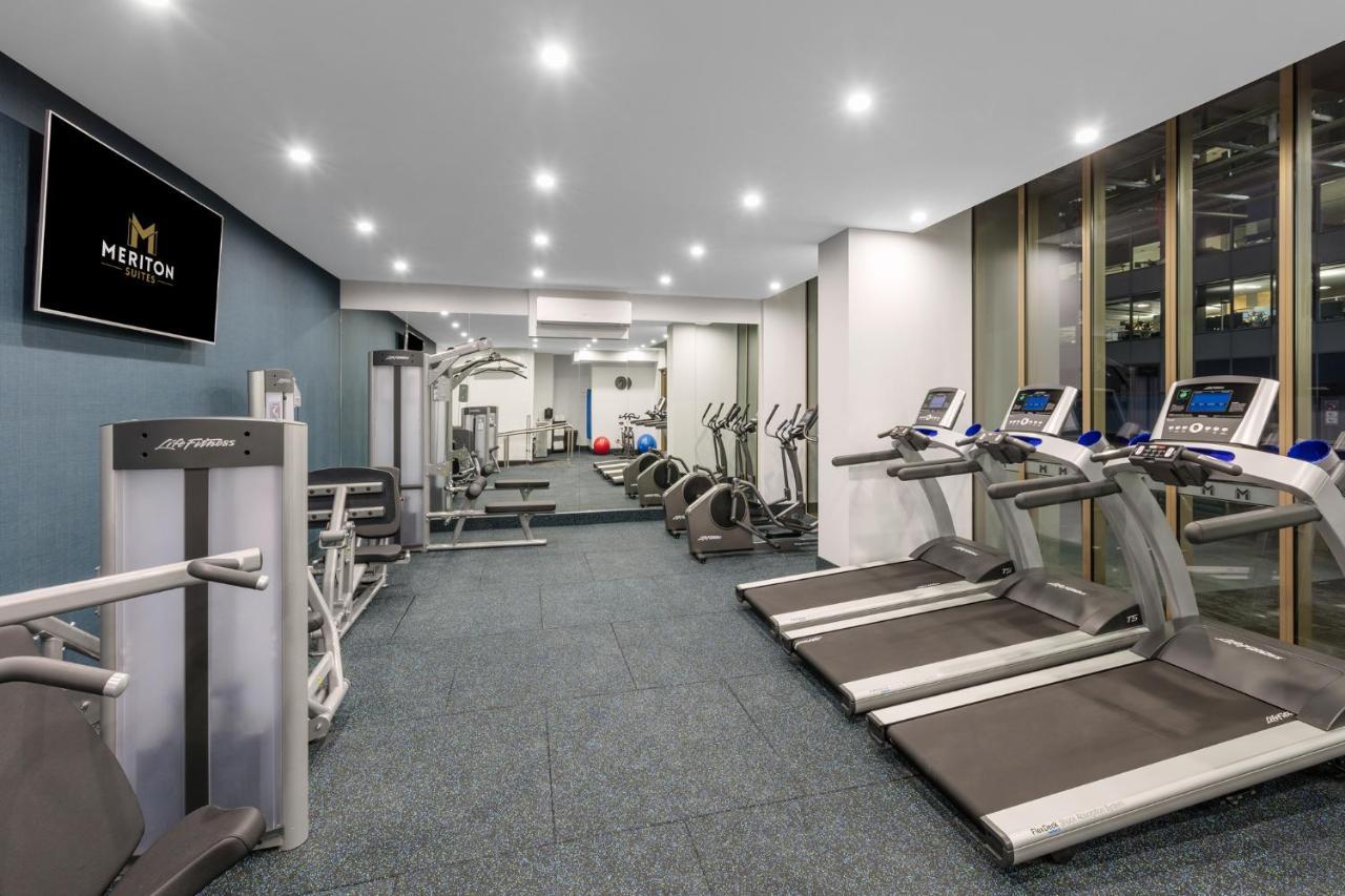 Meriton Suites Sussex Street, Sydney Exteriér fotografie The photo shows a modern gym space. It features various exercise equipment, including several treadmills and elliptical machines positioned along one side. On the other side, there are weight machines and additional fitness equipment. The gym has a c