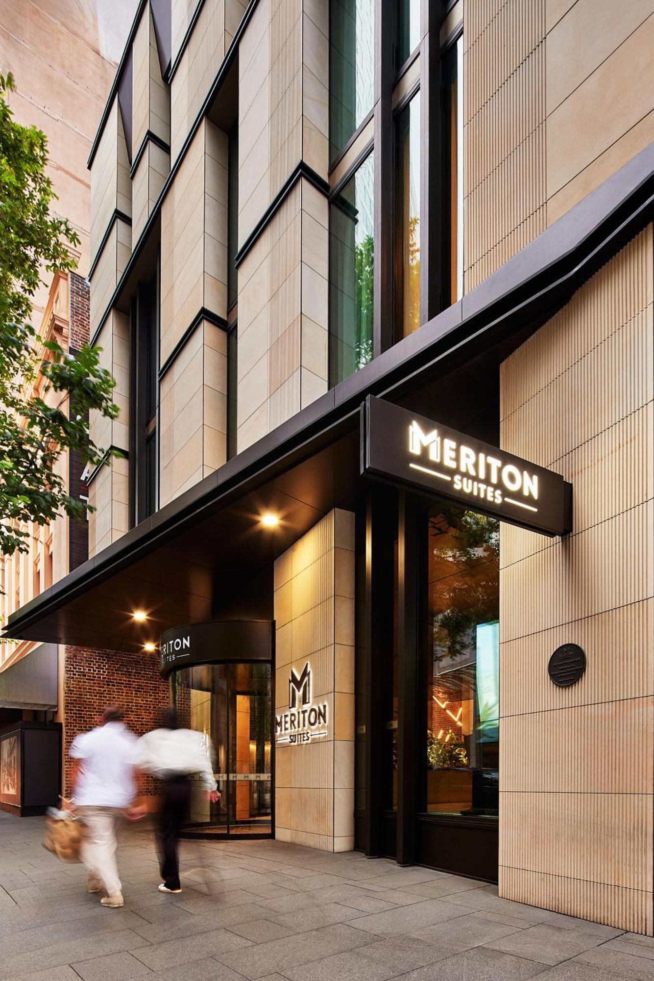 Meriton Suites Sussex Street, Sydney Exteriér fotografie The photo shows the exterior of a building with the signage for "Meriton Suites." The entrance features a modern design, with sleek architectural elements and large windows. The entrance is highlighted by a prominent awning and illuminated signs, ind